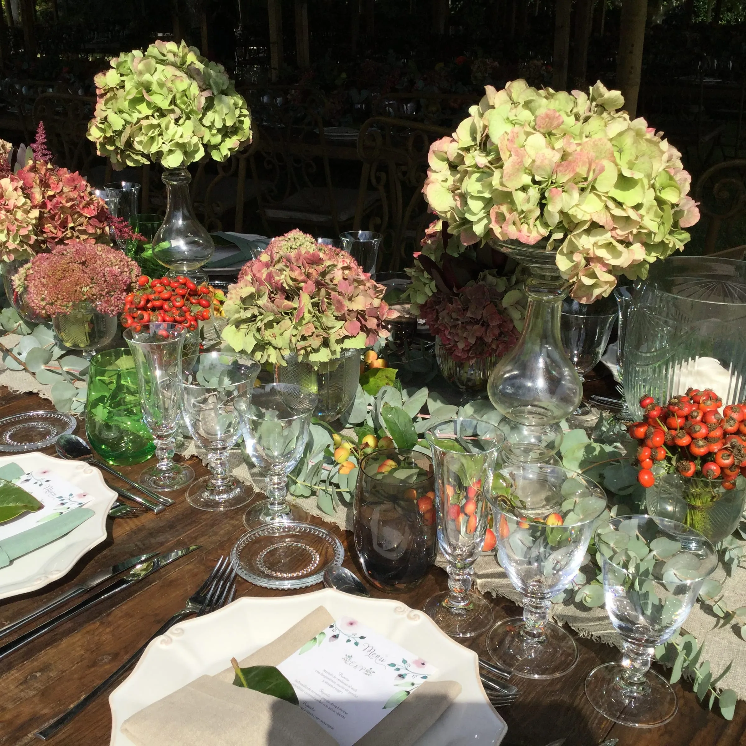 Night-time table with hydrangea and dried-flower centrepieces among glasses and candles