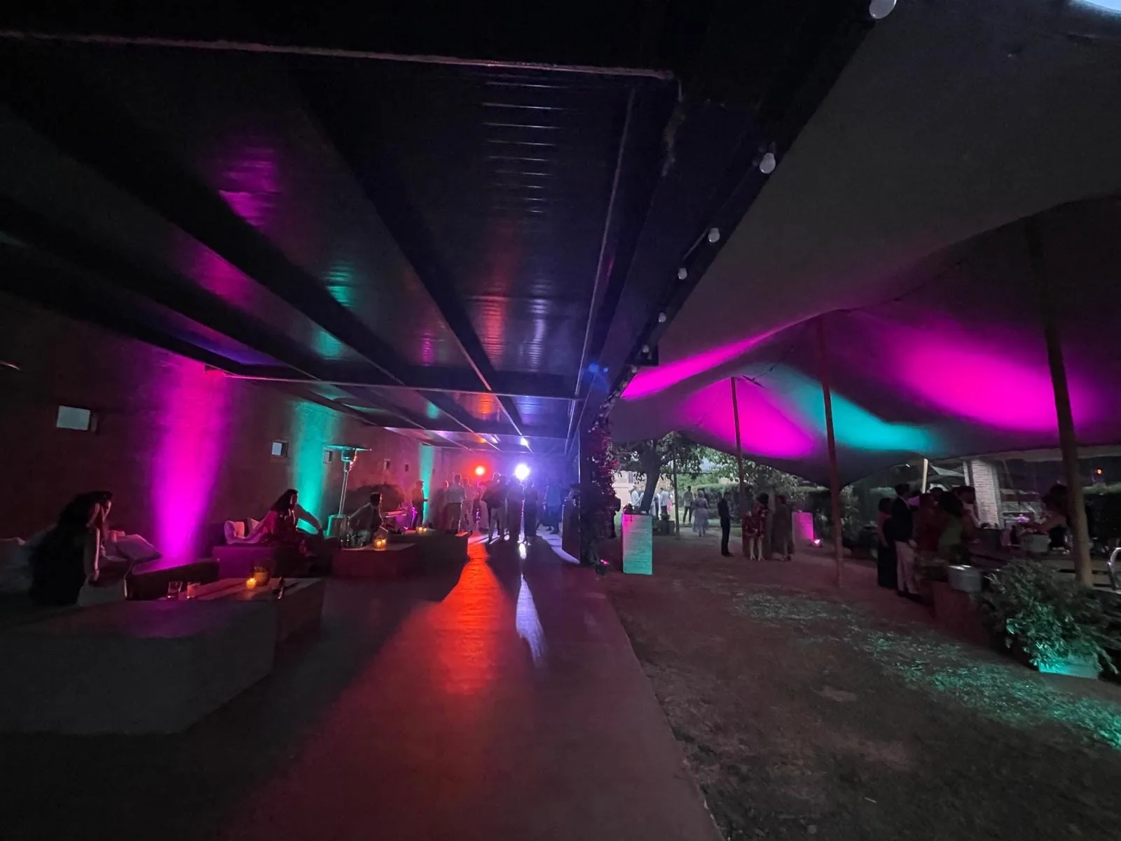 Dance floor under a marquee lit with pink and blue lights at night