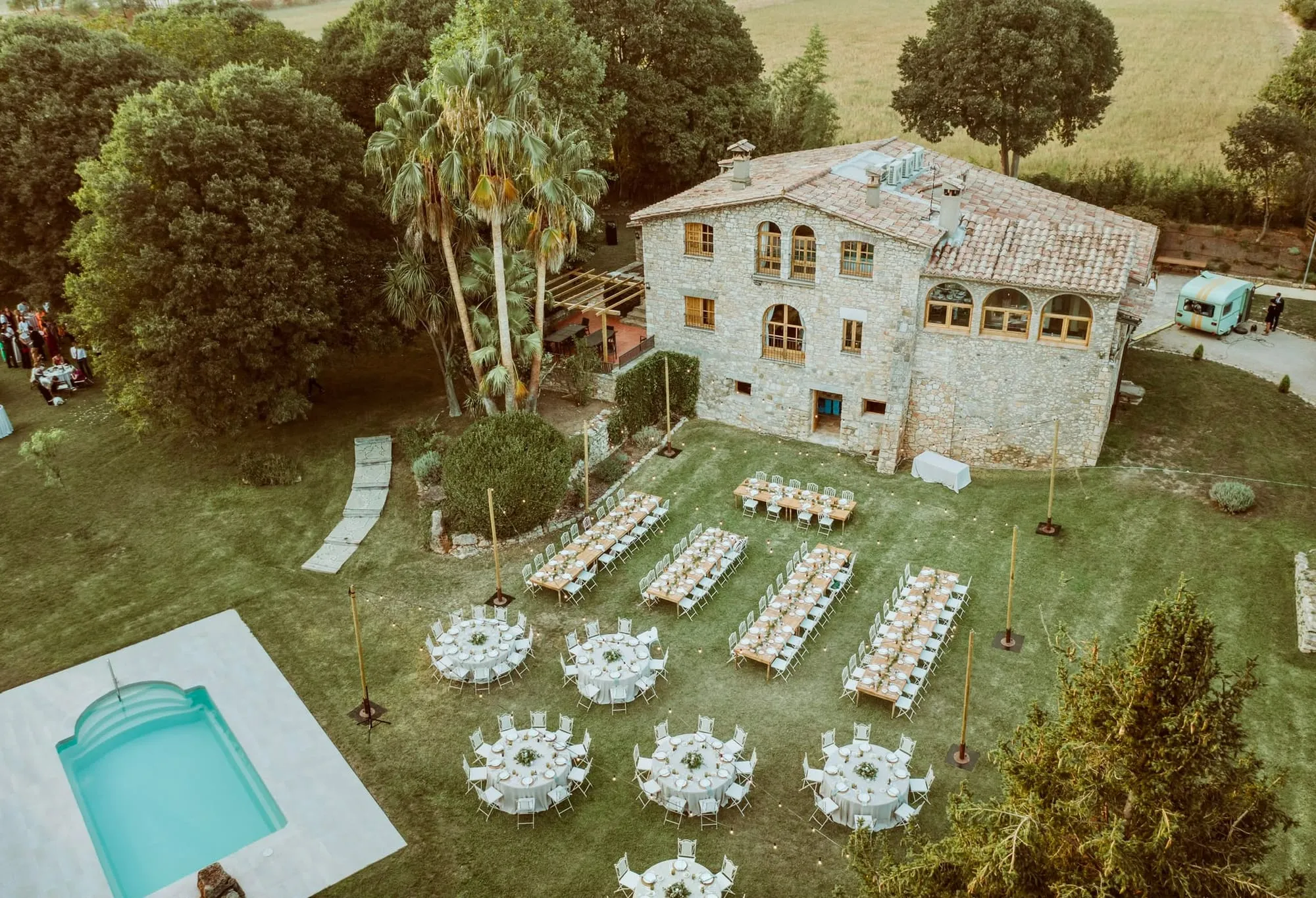 Vista aèria de la masia amb el jardí, la piscina i les taules del banquet parades a la gespa