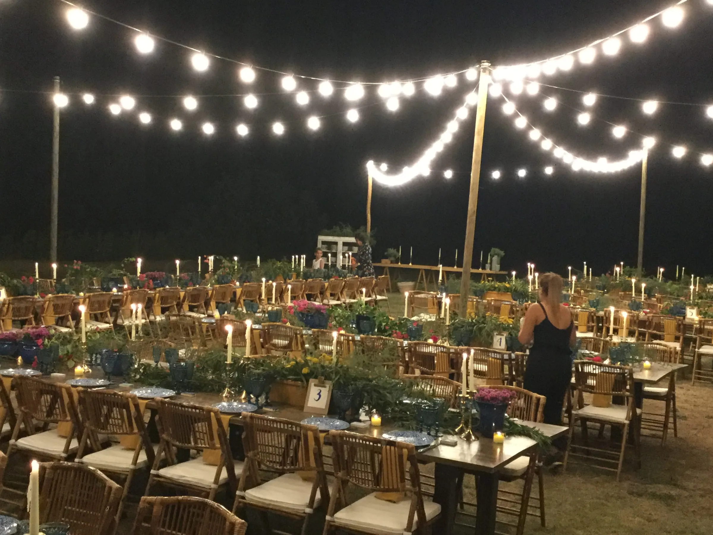 Banquet de nit al jardí, amb taules llargues sota garlandes de bombetes enceses