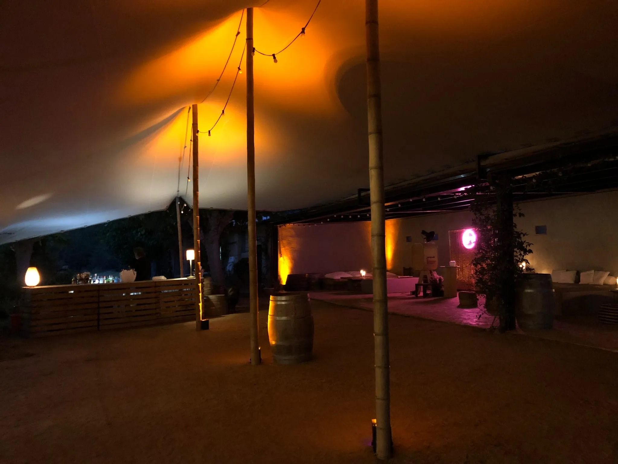Night party under a marquee lit with warm lights and wooden poles